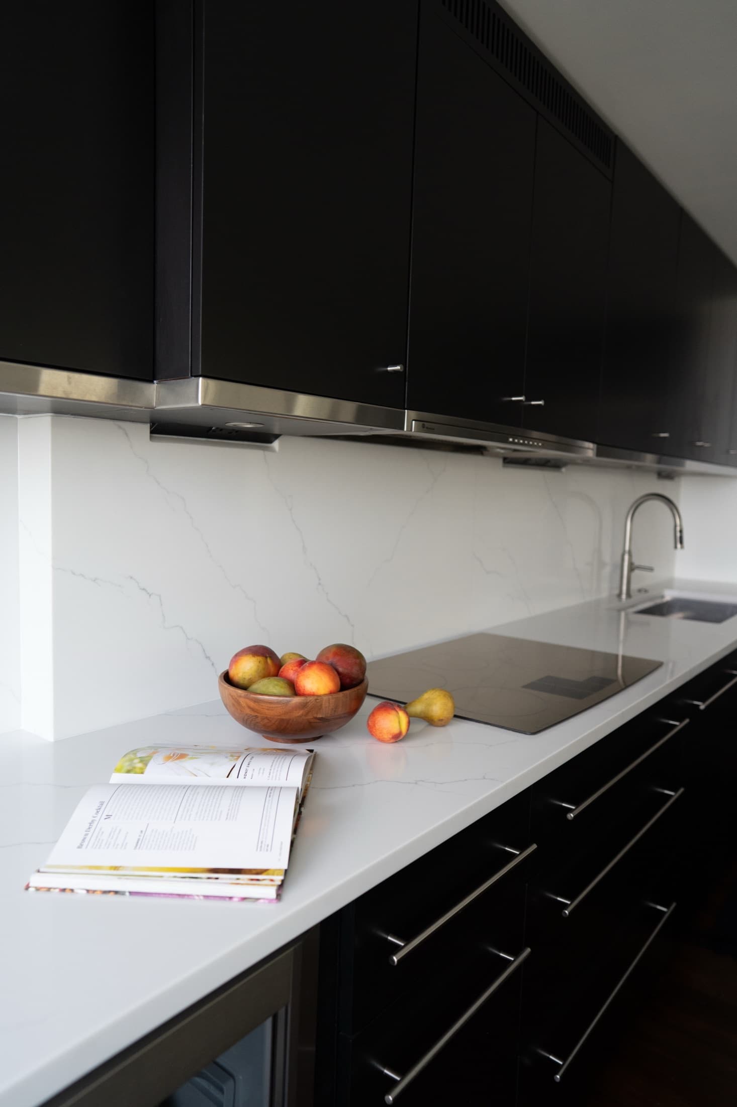 Detail of the Calacatta marble backsplash meeting the white quartz counter, with matte-black cabinetry above and below.